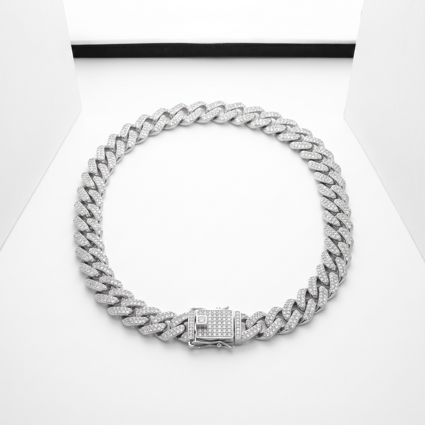 Iced Out 14MM Prong Cuban Link Chain in silver, laid on a white studio background