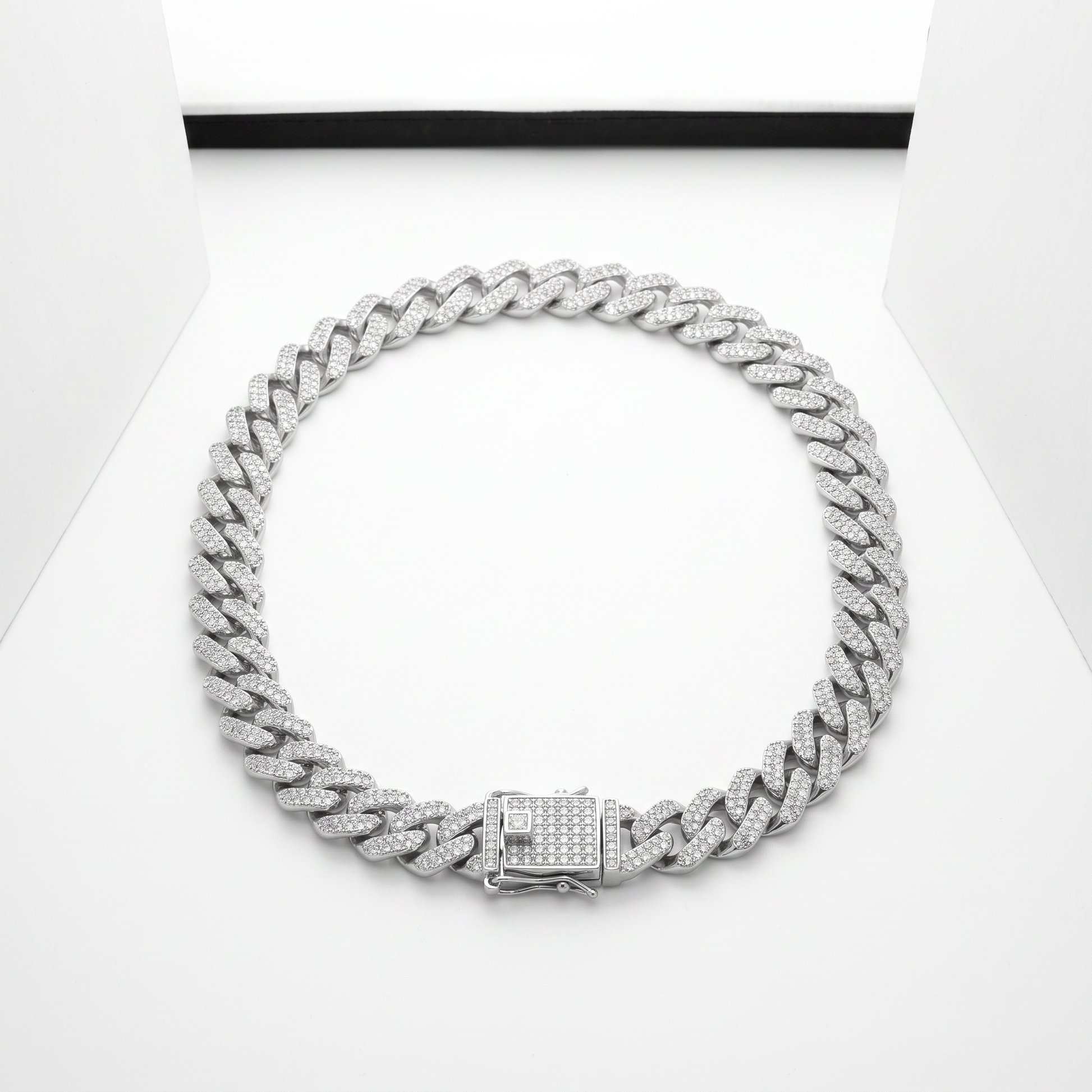 Iced Out 14MM Prong Cuban Link Chain in silver, laid on a white studio background